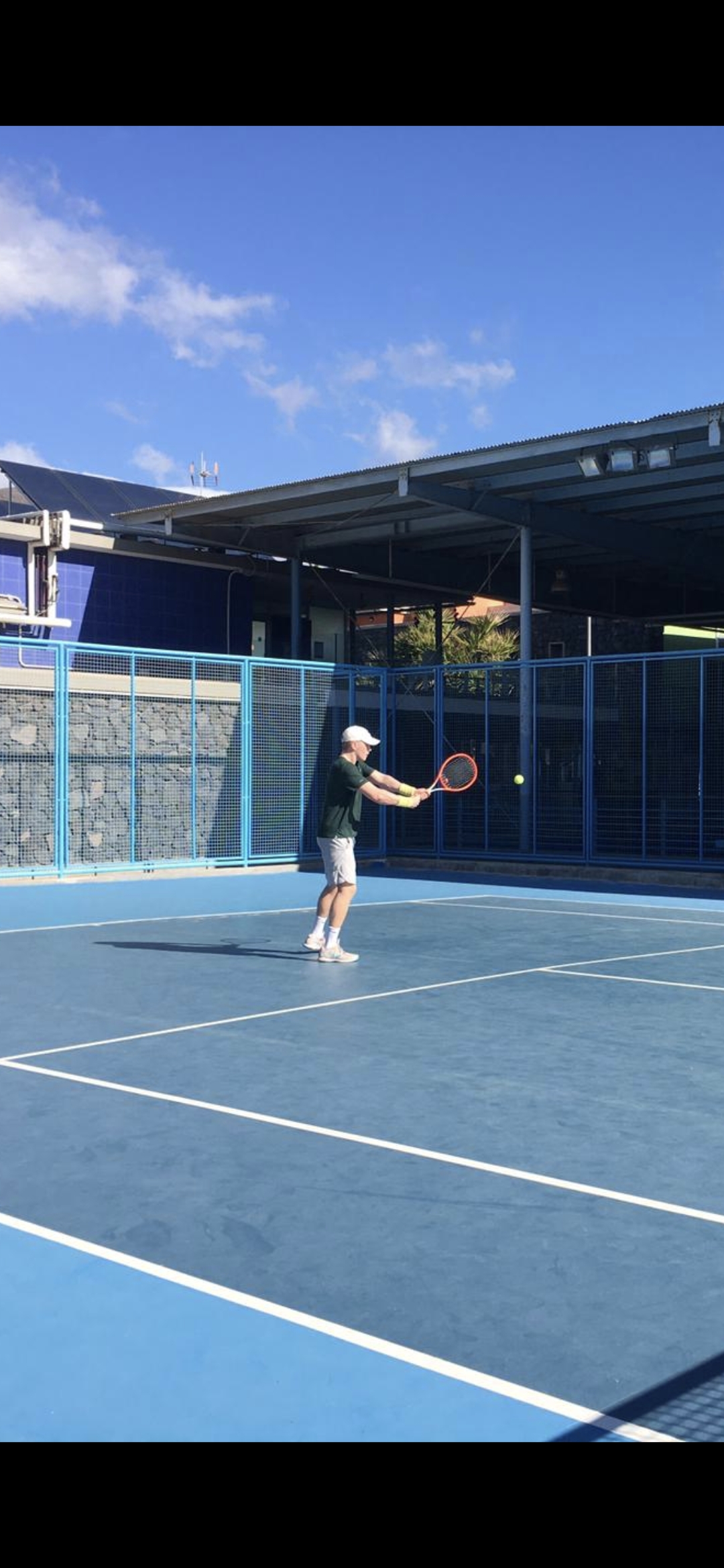 Joonas playing a backhand on an outdoor tennis court.